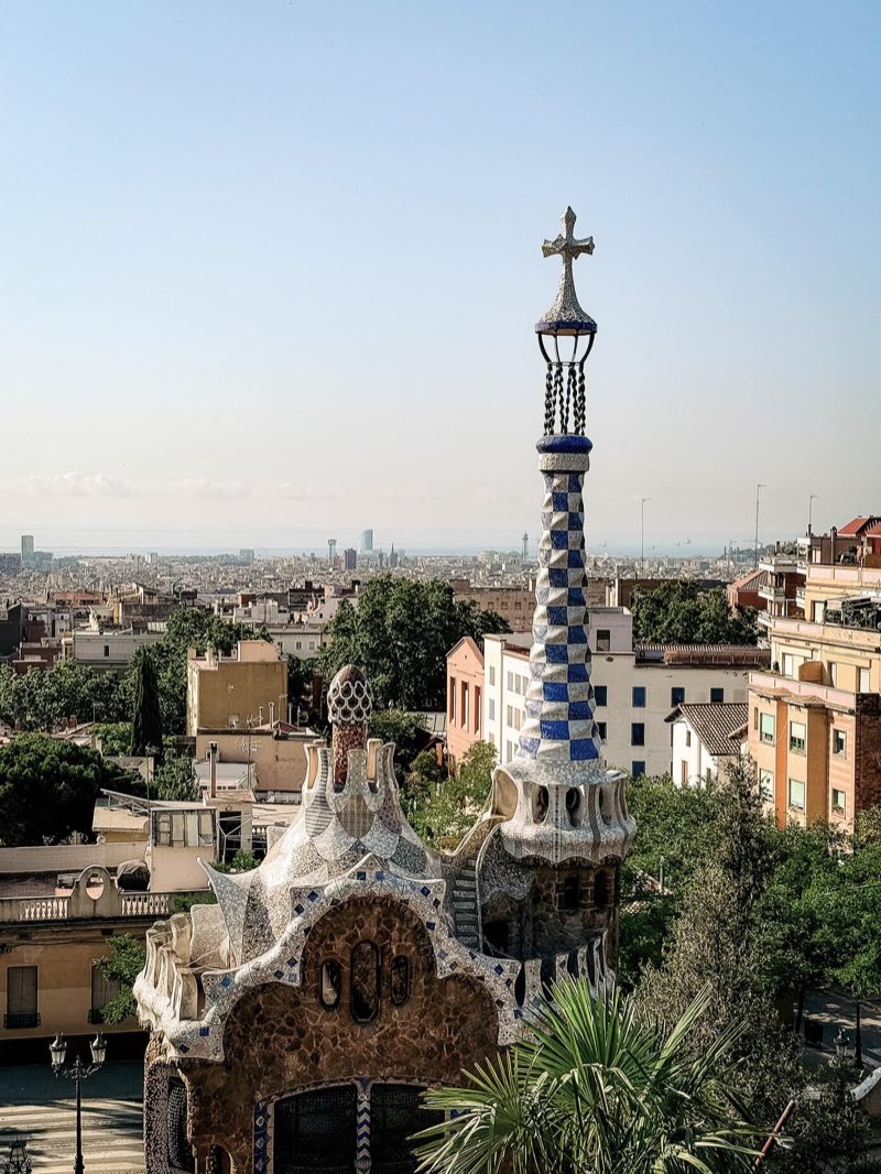 A mosaic spire of Park Güell above the Barcelona skyline